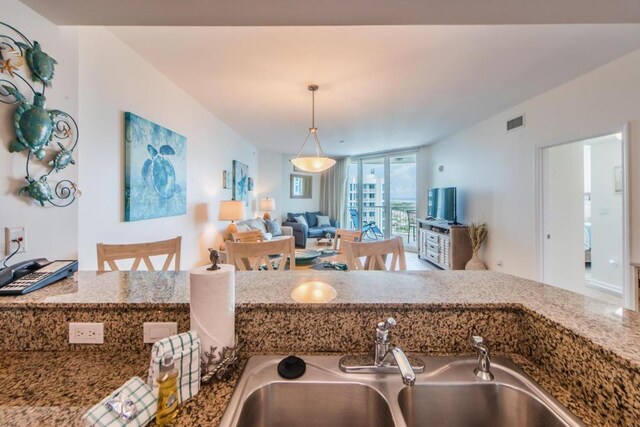 kitchen featuring stone countertops, sink, and decorative light fixtures