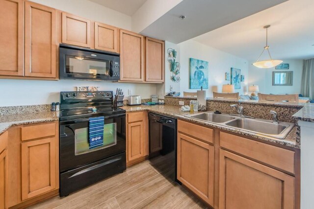 kitchen featuring pendant lighting, black appliances, kitchen peninsula, sink, and light hardwood / wood-style floors