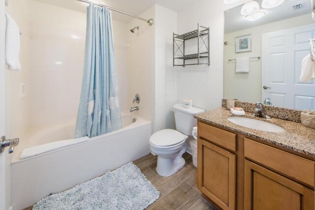 full bathroom featuring vanity, toilet, hardwood / wood-style floors, and shower / bathtub combination with curtain