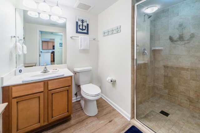 bathroom with vanity, toilet, hardwood / wood-style flooring, and a shower with shower door