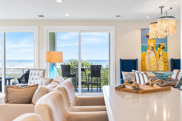 living area featuring a chandelier, visible vents, a healthy amount of sunlight, and a water view