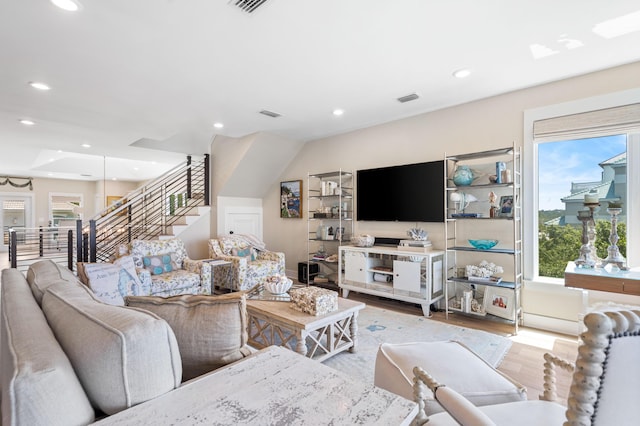 living room featuring a wealth of natural light, stairway, and wood finished floors