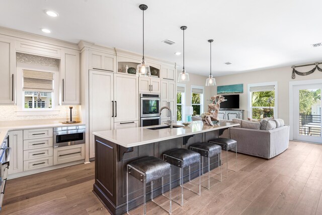 kitchen featuring a breakfast bar area, light hardwood / wood-style floors, a kitchen island with sink, stainless steel appliances, and sink