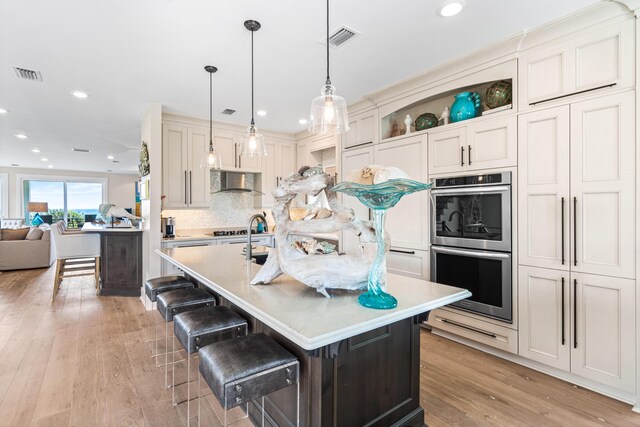 kitchen with light countertops, light wood-type flooring, visible vents, and stainless steel double oven