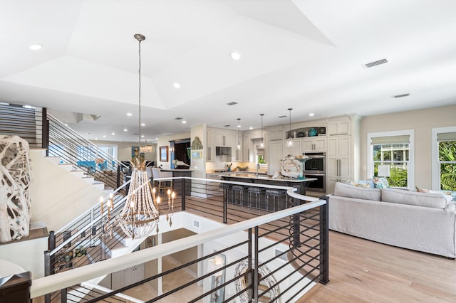 kitchen with pendant lighting, light hardwood / wood-style floors, stainless steel appliances, a chandelier, and lofted ceiling