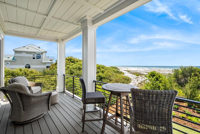 wooden terrace featuring a water view and a view of the beach