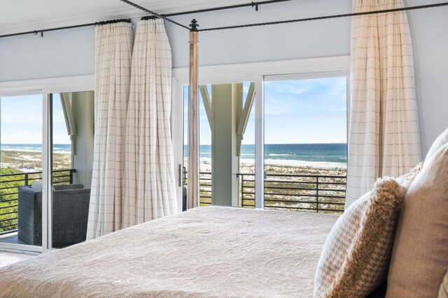 bedroom with a water view, multiple windows, and a beach view