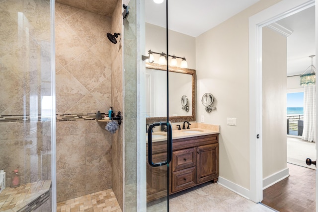bathroom with baseboards, tiled shower, and vanity