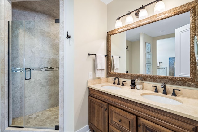 bathroom with double vanity, baseboards, a stall shower, and a sink