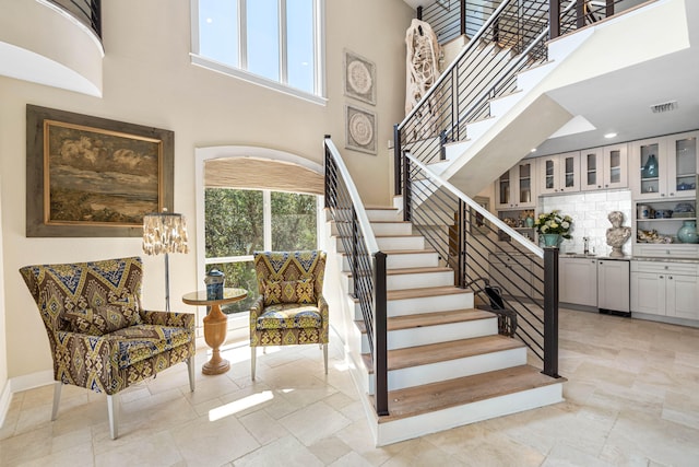 stairway featuring a healthy amount of sunlight and a high ceiling