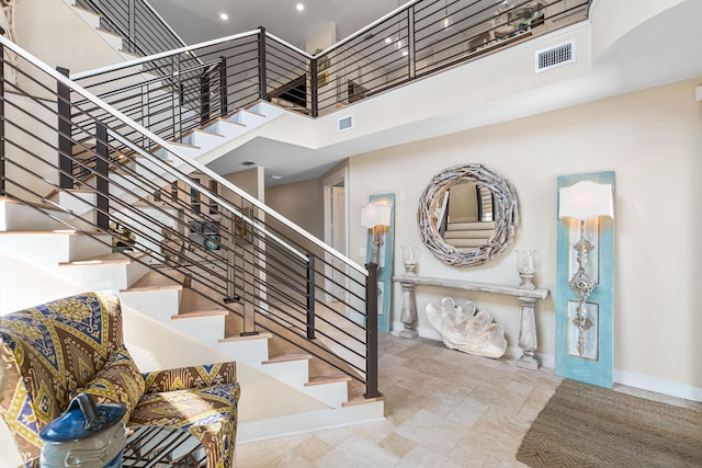 stairway with a high ceiling, baseboards, and visible vents