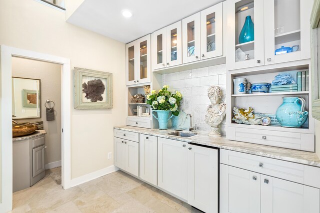 bar featuring sink, light stone countertops, decorative backsplash, and white cabinets