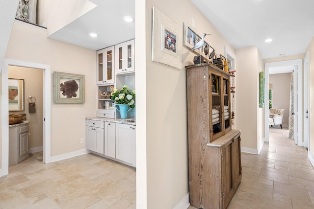 corridor featuring stone tile floors, recessed lighting, and baseboards