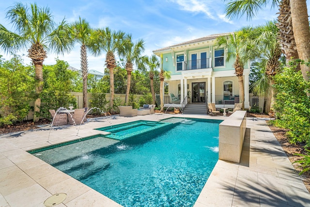 back of house with a patio area, a balcony, a pool with connected hot tub, and fence