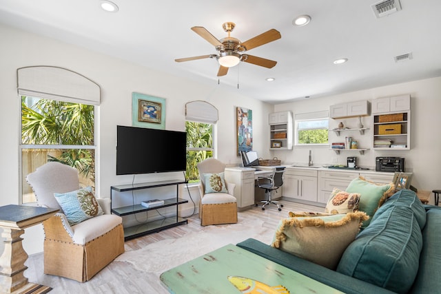living room featuring light wood finished floors, visible vents, and ceiling fan