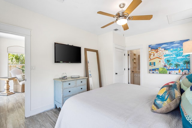 bedroom featuring a ceiling fan, visible vents, baseboards, ensuite bathroom, and light wood-type flooring
