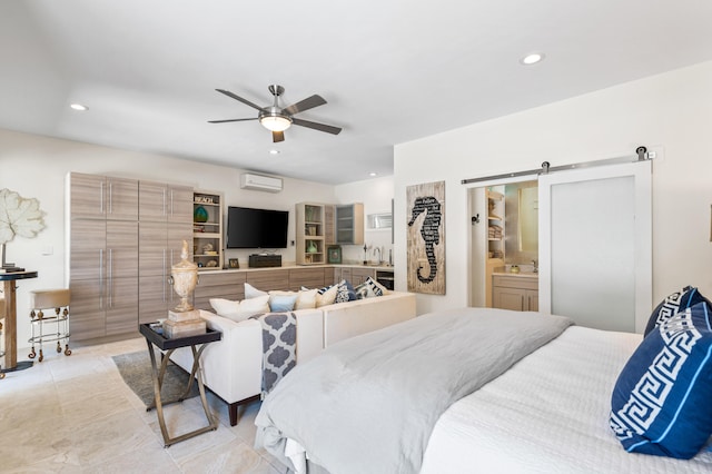 bedroom featuring an AC wall unit, connected bathroom, ceiling fan, and a barn door