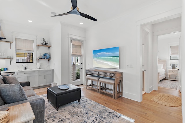 living room with light hardwood / wood-style flooring, ceiling fan, and sink