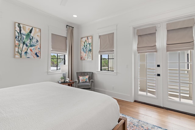 bedroom featuring multiple windows, access to outside, light hardwood / wood-style flooring, and french doors