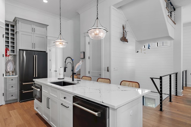 kitchen featuring appliances with stainless steel finishes, a center island with sink, sink, and light hardwood / wood-style floors