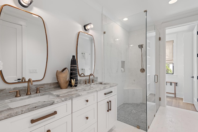 bathroom with a shower with shower door, hardwood / wood-style floors, and vanity