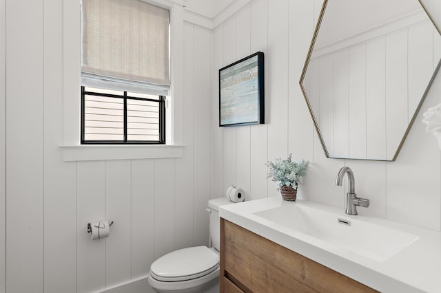 bathroom with vanity, toilet, and wooden walls