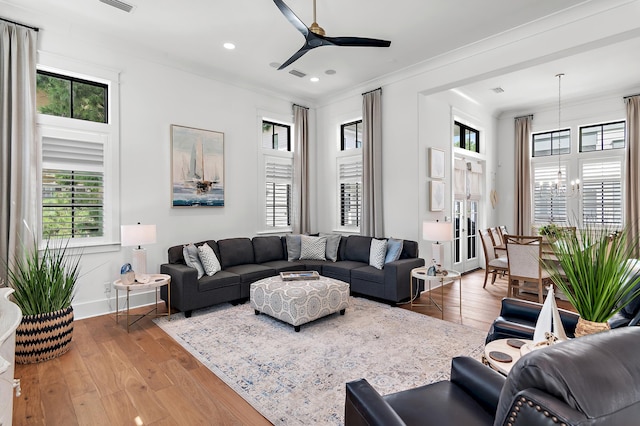 living room with ceiling fan with notable chandelier, hardwood / wood-style flooring, and a healthy amount of sunlight