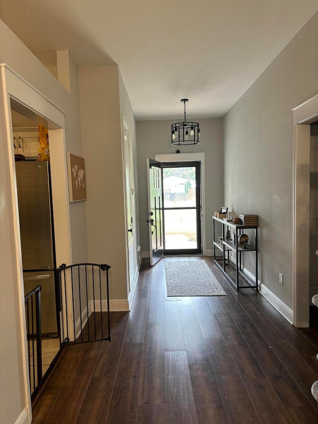 doorway to outside with an inviting chandelier and dark wood-type flooring