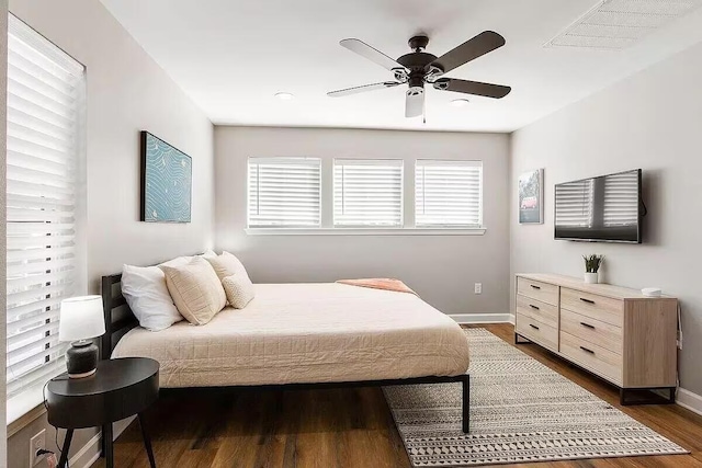 bedroom with multiple windows, dark hardwood / wood-style flooring, and ceiling fan