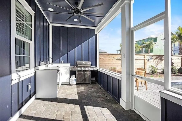 unfurnished sunroom with ceiling fan and sink