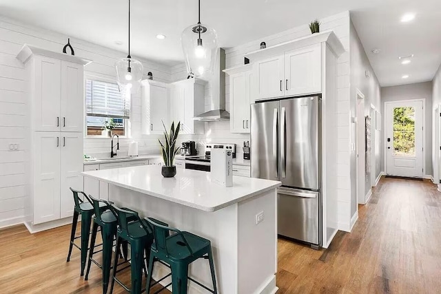 kitchen featuring white cabinets, a center island, stainless steel appliances, and light hardwood / wood-style flooring