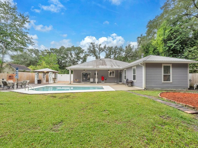 rear view of house featuring a lawn, a fenced in pool, and a patio