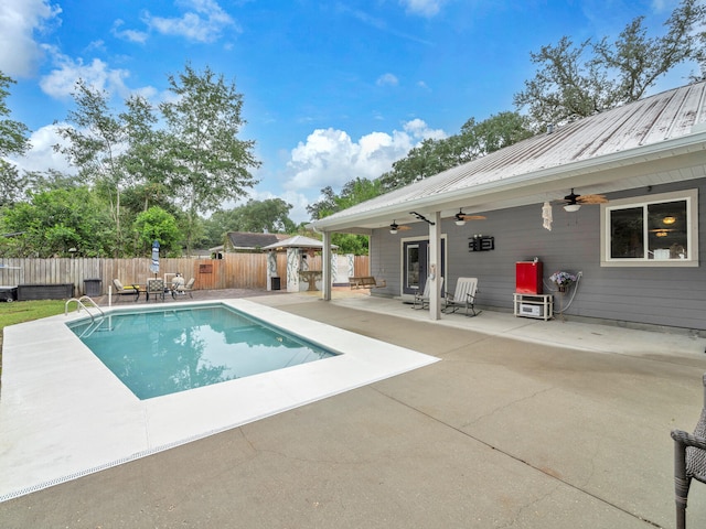 view of pool with an outbuilding, a ceiling fan, a shed, a fenced backyard, and a patio area