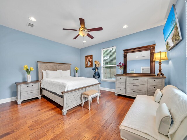 bedroom featuring visible vents, ceiling fan, baseboards, and hardwood / wood-style flooring