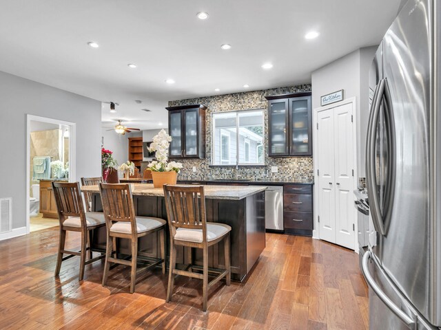 kitchen featuring a kitchen bar, stainless steel appliances, a center island, dark hardwood / wood-style floors, and dark brown cabinetry