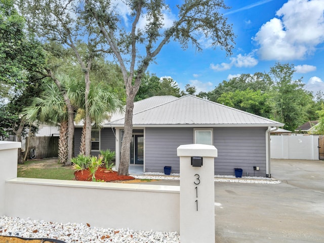 ranch-style home featuring metal roof and fence