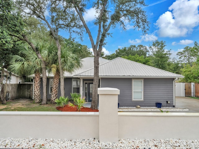 view of front of home featuring metal roof, fence private yard, and a gate