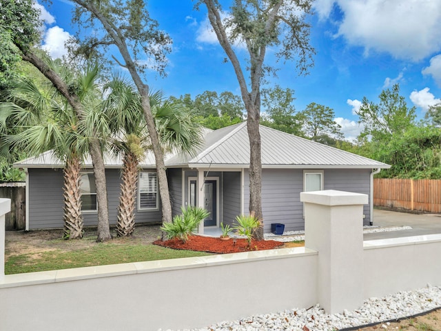 mid-century home with a fenced front yard and metal roof