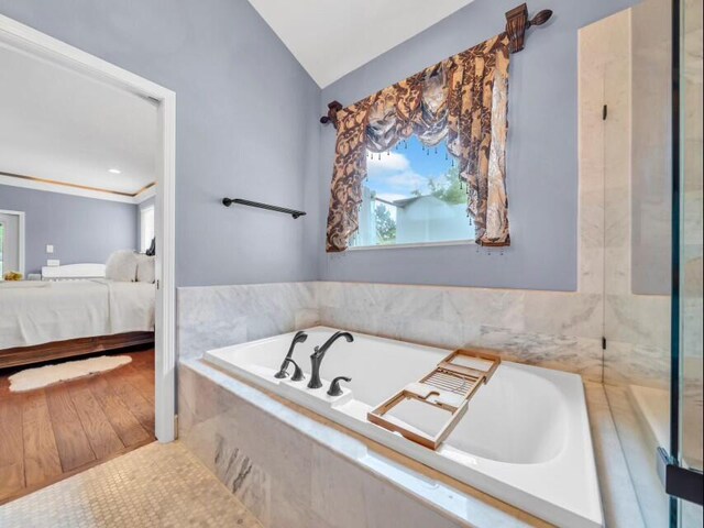 bathroom featuring lofted ceiling, hardwood / wood-style flooring, and plus walk in shower