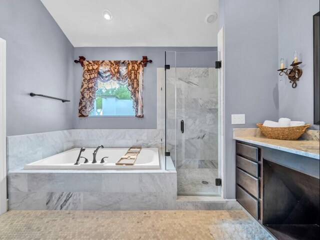 bathroom featuring vanity, a garden tub, and a marble finish shower