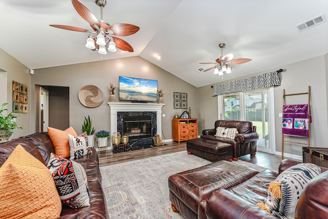 living room featuring a premium fireplace, vaulted ceiling, ceiling fan, and hardwood / wood-style floors