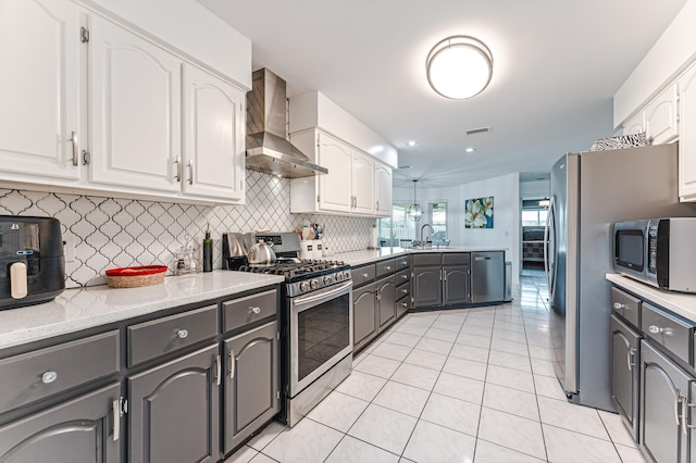 kitchen featuring white cabinets, appliances with stainless steel finishes, and wall chimney range hood