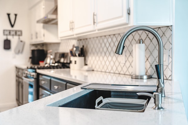 kitchen with white cabinetry, stainless steel range, tasteful backsplash, and ventilation hood