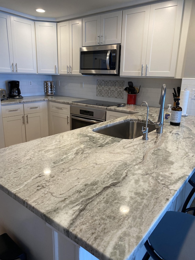 kitchen featuring a breakfast bar area, appliances with stainless steel finishes, backsplash, and white cabinetry