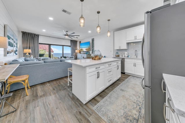 kitchen featuring white cabinetry, pendant lighting, stainless steel appliances, a center island, and ceiling fan