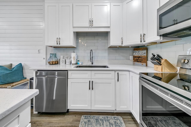 kitchen featuring appliances with stainless steel finishes, dark wood-type flooring, sink, and white cabinetry