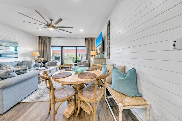 dining room with wooden walls, ceiling fan, and hardwood / wood-style flooring