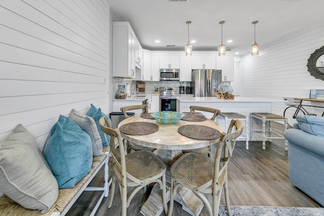 dining room featuring wood walls, light hardwood / wood-style floors, and sink