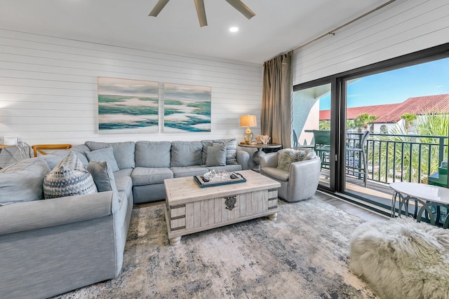 living room featuring ceiling fan and wooden walls