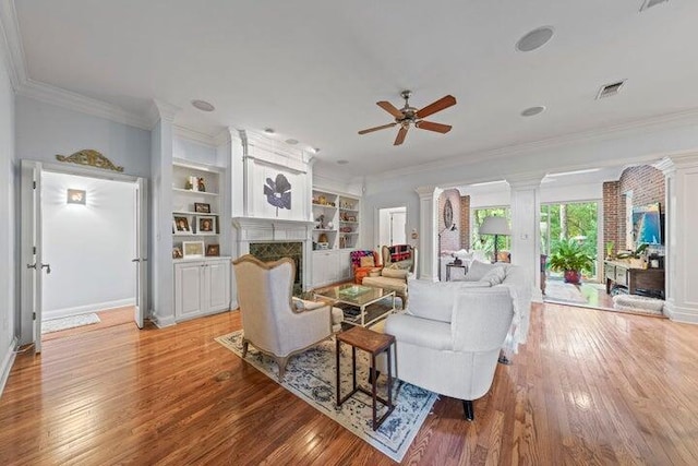 living room with crown molding, built in features, ceiling fan, and light hardwood / wood-style floors